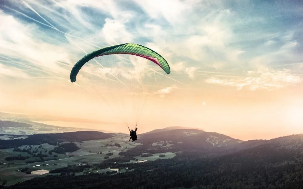 Vue de dos d'un vol en parapente biplace au-dessus des montagnes