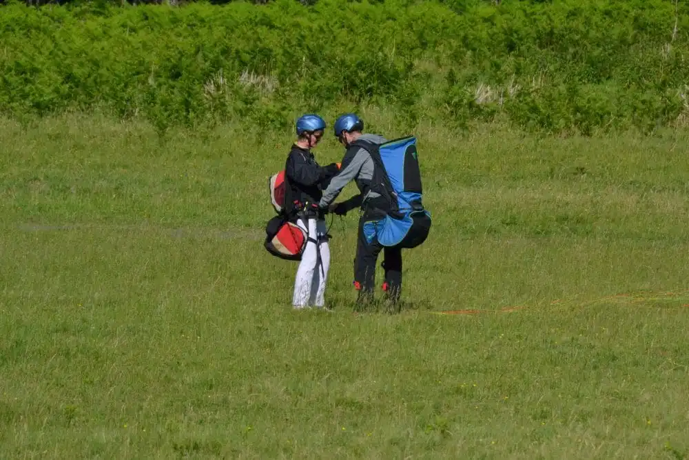 Moniteur attachant et sécurisant le harnais d'un passager avant le vol biplace