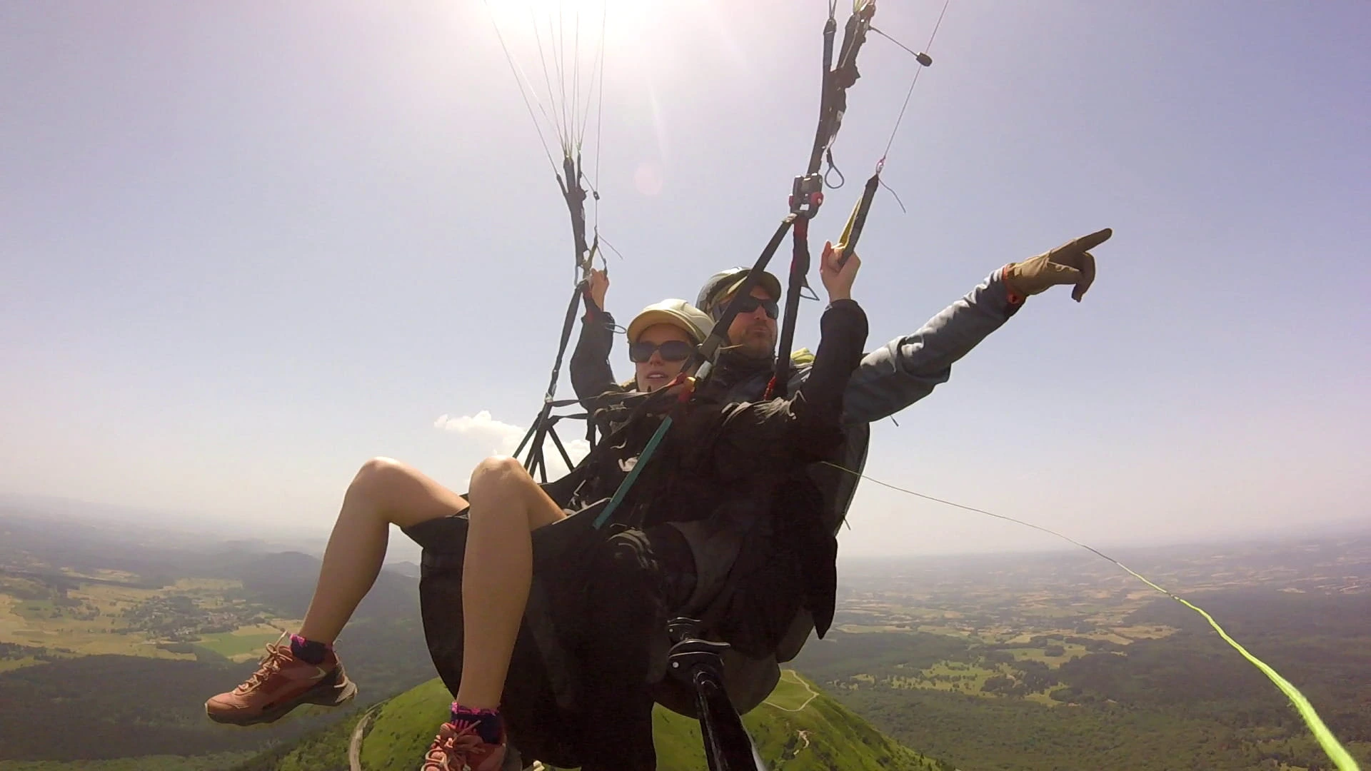 Moniteur montrant l'horizon et expliquant le paysage à un passager en plein vol en parapente
