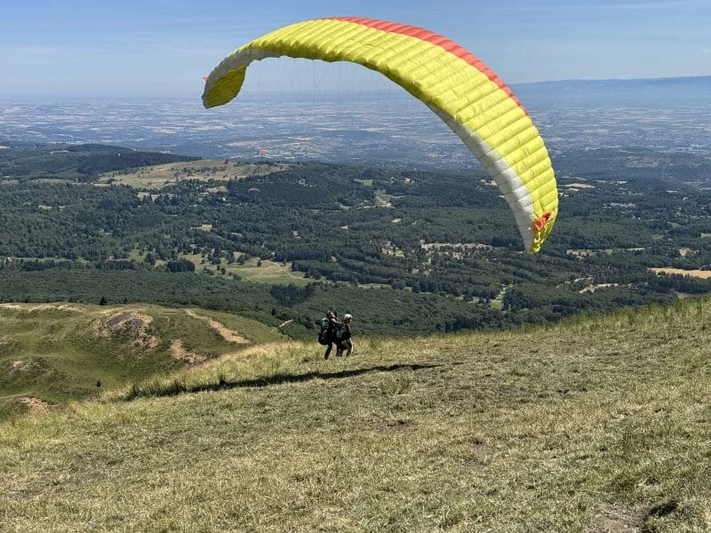 Passager et moniteur effectuant quelques pas de course en douceur lors du décollage en parapente